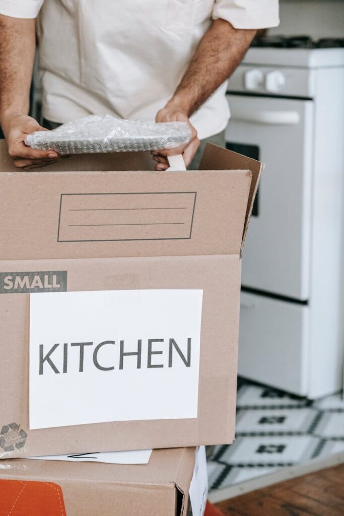 Man packing kitchenware into labeled boxes for a home relocation.